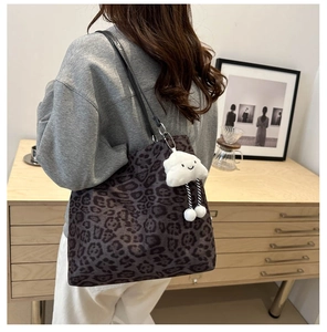 Close-up of leopard print tote bag with white cloud plush charm and leather strap