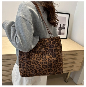 Side view of large leopard print tote bag with brown leather straps worn by model