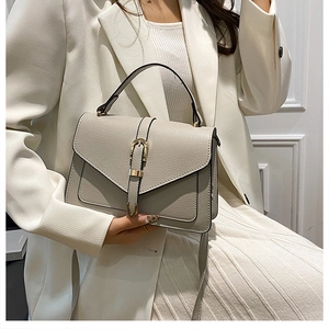 Detail of grey pebbled leather handbag featuring a vintage gold clasp and elegant top handle