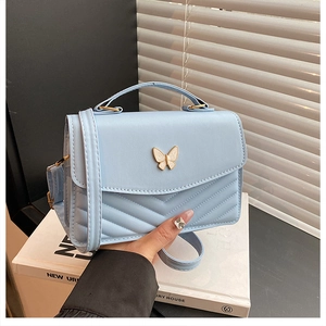 Détail du sac à bandoulière bleu clair avec boucle papillon perlée et matelassage en V