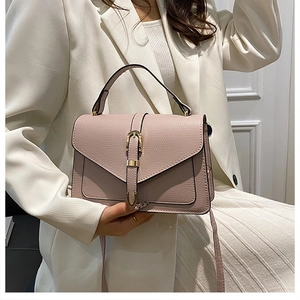 Close-up of pink pebbled leather handbag with gold buckle and top handle details
