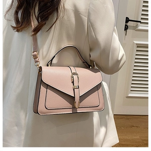 Close-up of pink lychee textured leather crossbody bag with golden buckle on white suit