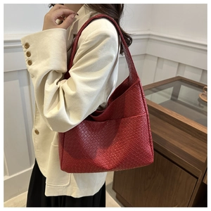 Close-up of woven PU leather texture and strap detail on a reddish-brown shoulder bag