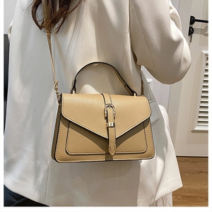 Close-up of stylish brown pebble leather crossbody bag with decorative strap buckle