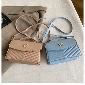 Détail de sacs à bandoulière en cuir avec fermoir papillon et coutures en V matelassées