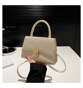 Macro detail of cream crossbody bag featuring glittering sequins and golden metal turn lock
