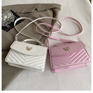 Détail de sacs à bandoulière blanc et rose avec matelassage en V et boucle papillon