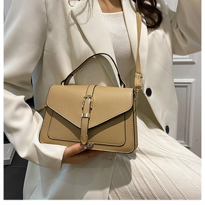 Close-up of khaki leather handbag with gold buckle styled with a white blazer outfit