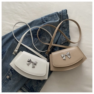 Detail of mini crossbody bags with silver metal bow on smooth PU leather over denim