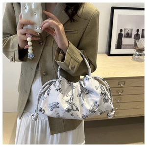 Detailed close-up of a white pleated cloud bag with elegant black butterfly prints