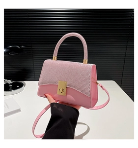 Detailed macro view of pink glitter texture on a square crossbody handbag with gold lock