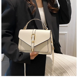 Modern cream leather crossbody bag with golden horsebit detail on a black blazer outfit