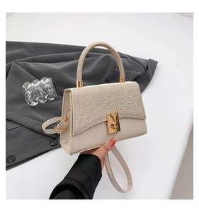 Detail of elegant cream leather handbag with gold textured fabric and rotating metal clasp