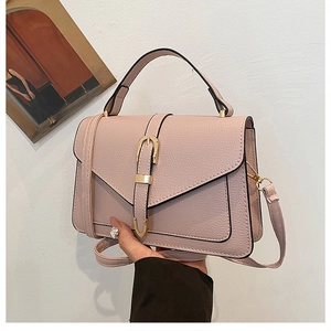 Detailed macro view of pink lychee grain leather handbag with gold buckle and top handle