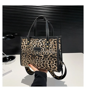 Detail of leopard print tote bag with black leather handle and LOVE patterned shoulder strap