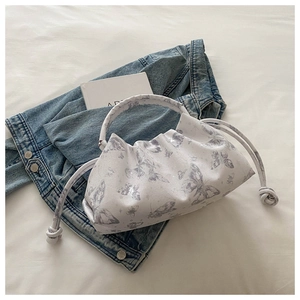 Macro view of butterfly print on pleated white cloud bag with drawstring and knot detail