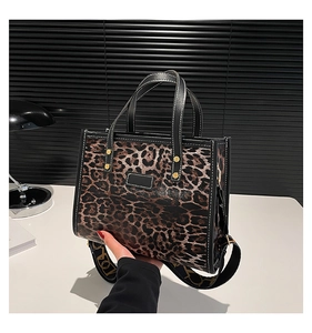 Detailed view of leopard print tote bag with black leather trim and wide shoulder strap