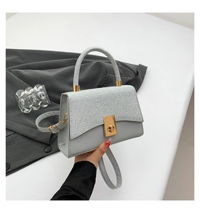 Detail of grey crossbody bag with silver glitter flap and gold rectangular twist lock