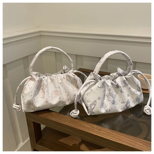 Detail of drawstring shoulder bags featuring butterfly prints and pleated side texture