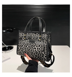 Macro shot of leopard print tote bag with black trim and gold rivet details