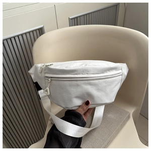 Gros plan détaillé d'un sac bandoulière blanc à carreaux avec fermeture triangulaire