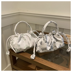 Detail of butterfly printed pleated bags with drawstring design in green and grey colors