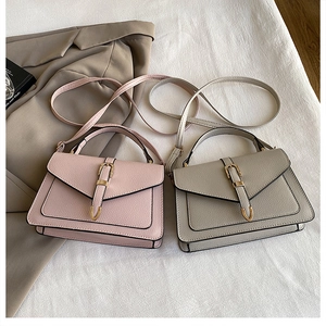 Flat lay of pink and grey litchi texture leather handbags with golden U-shaped buckles