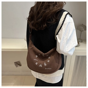 Detailed texture of brown corduroy crescent bag with white embroidered fashion logo