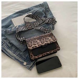 Detailed view of leopard print crossbody bag with black pocket and wide geometric strap