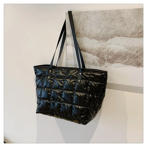 Detailed view of black quilted down tote bag featuring glossy nylon and diamond stitching