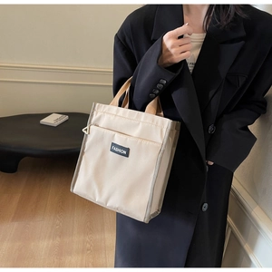 Détail d'un sac cabas en toile avec étiquette en cuir et anses en tissu contrasté