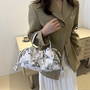 Chic pleated white shoulder bag with black butterfly prints and drawstring detail