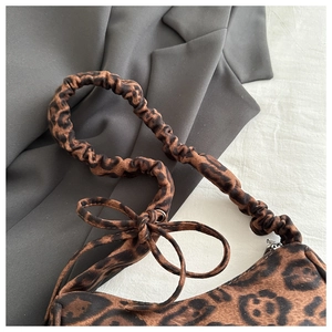 Detail of leopard print shoulder bag with scrunchie strap and bow on gray blazer