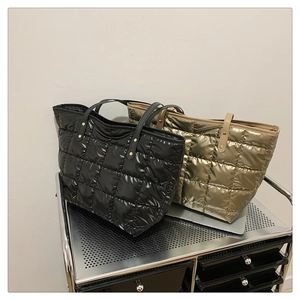 Detail of quilted puffer tote bags in black and champagne gold with metal stud reinforcement