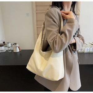 Detailed view of cream white soft leather tote bag with natural wrinkles and wide shoulder strap