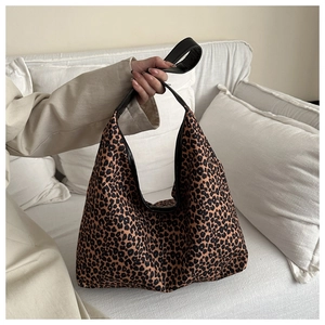 Close-up of leopard print hobo bag with black leather trim on a white sofa backdrop