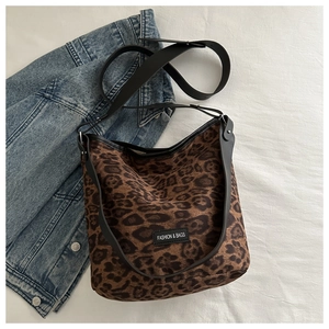 Détail du sac cabas en daim léopard avec lanières en cuir noir et étiquette textile