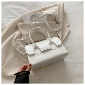 Detailed view of white leather crossbody bag with minimalist handle on beige blazer