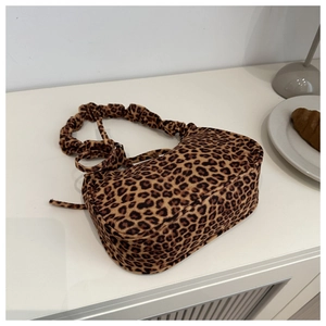 Dettaglio della borsa leopardata con manico arricciato alla moda su sfondo neutro