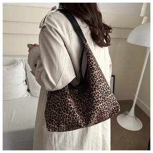Detail of a large leopard print shoulder bag with black leather strap on a model