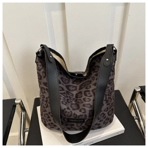 Détail macro du sac cabas léopard avec bretelles noires et étiquette de marque en cuir