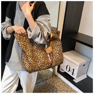 Detailed view of leopard print tote bag featuring a cute brown plush bear charm accessory