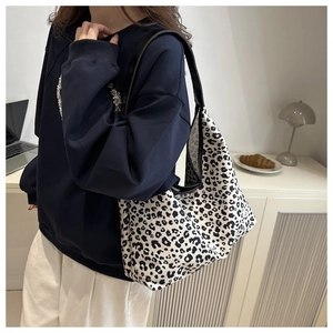 Detailed view of leopard print shoulder bag with black leather strap on a model