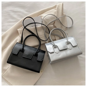 Chic box-shaped crossbody bags in black and silver shown on a minimalist suit jacket