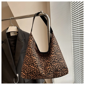 Detailed close-up of leopard print hobo bag with a wide black shoulder strap and canvas texture