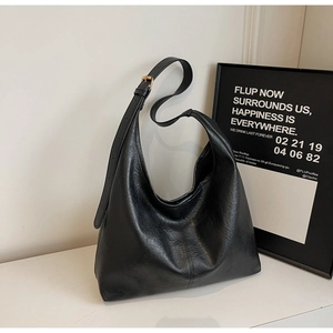 Detail of minimalist black hobo bag showing retro wrinkled faux leather texture and strap