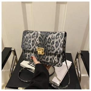 Close-up of leopard print crossbody bag with gold metal buckle and textured finish