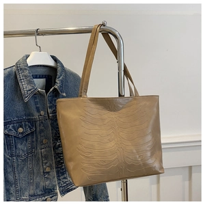 Detail of embossed rib cage pattern on a large camel PU leather tote bag surface