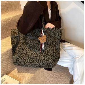 Large leopard print tote bag with plush bear charm shown in a casual lifestyle setting