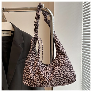 Leopard print crossbody bag with drawstring pleated shoulder strap on a grey blazer